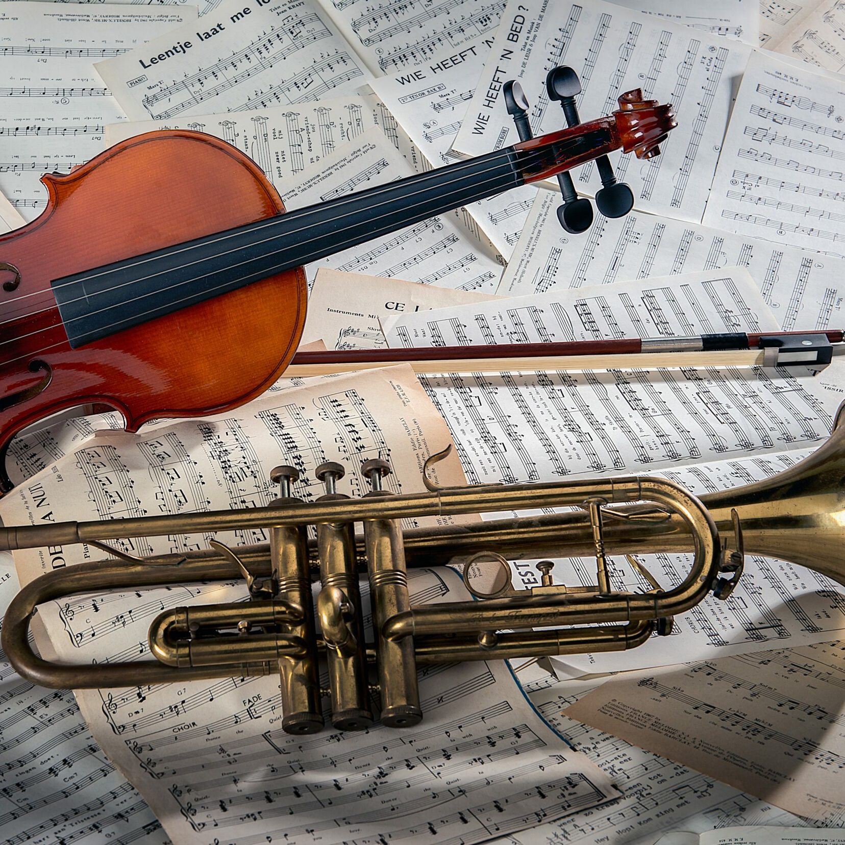 Closeup of a violin and a trumpet on note sheets under the lights - perfect for musical concepts